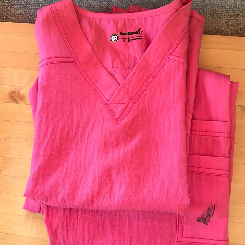 WanderLink four stretch light pink scrubs has a little black stain on the pocket